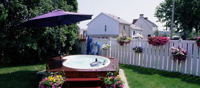 A hot tub in a back yard with umbrella and stairs