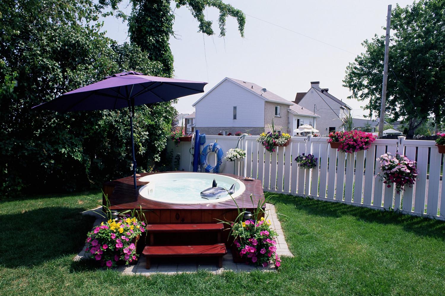 A hot tub in a back yard with umbrella and stairs