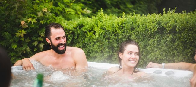 Smiling young couple enjoying their hot tub on a summer day