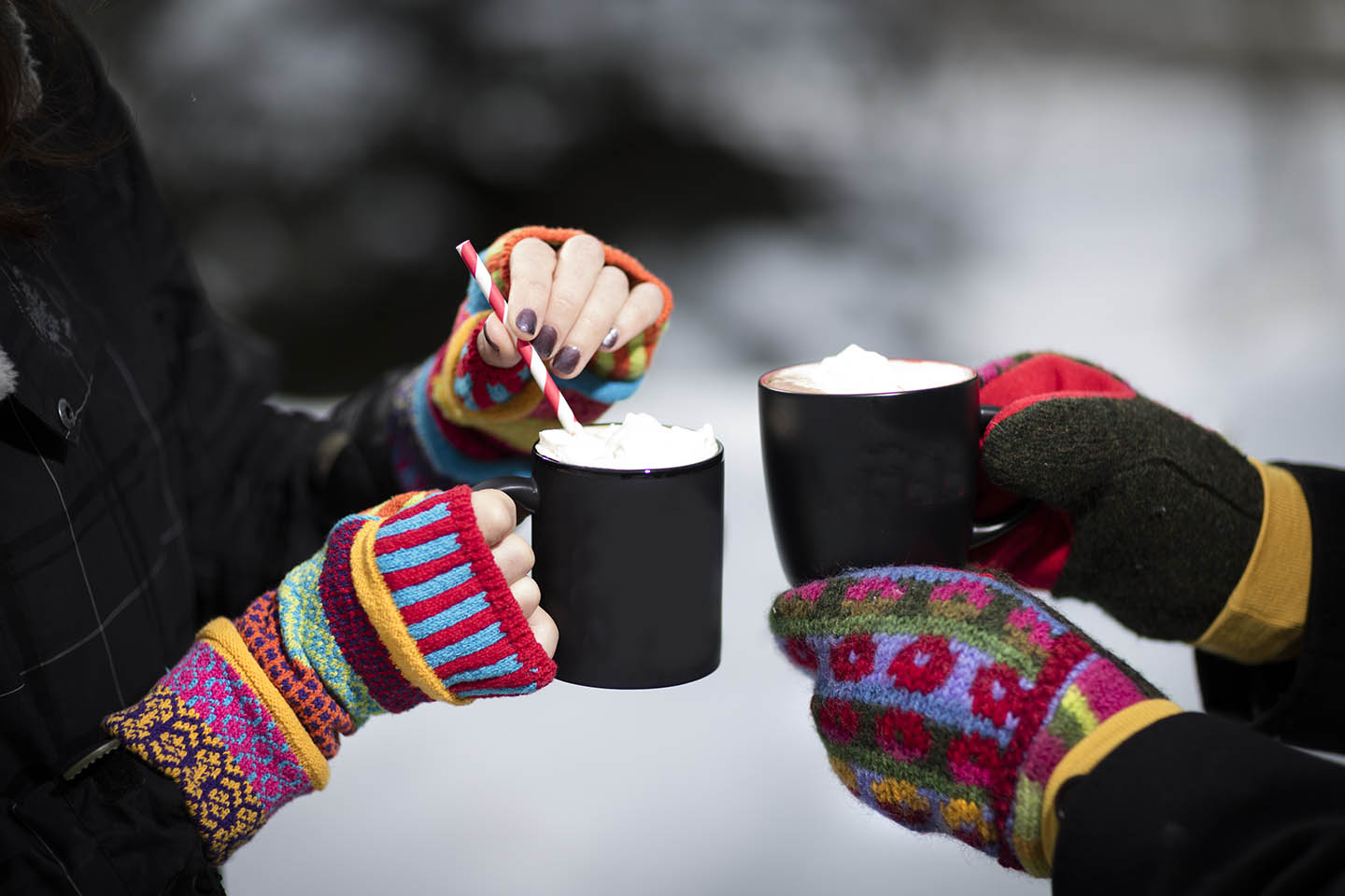 Two girls in fingerless gloves holding hot cocoa