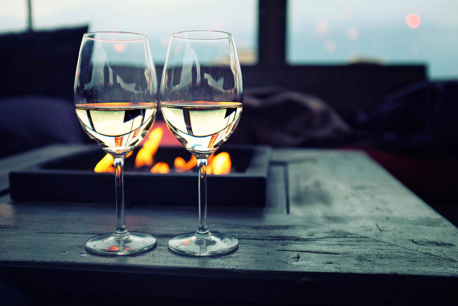 Two glasses of white wine near an outdoor fire