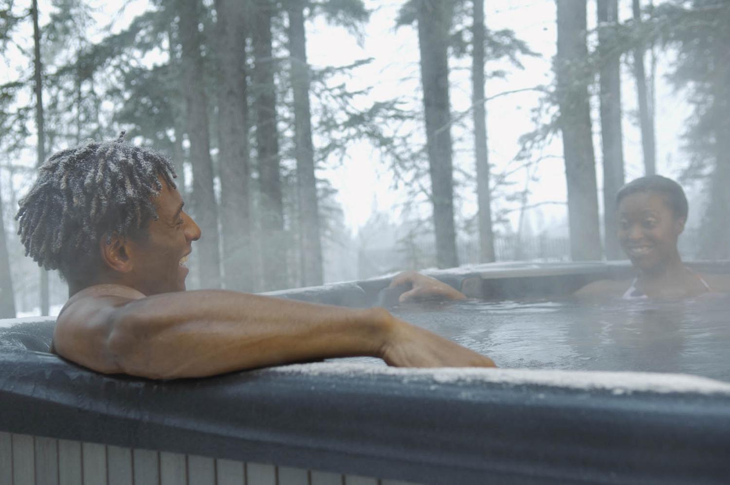 Smiling couple in outdoor hot tub in winter